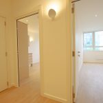 Bright hallway with open bedroom doors in apartment.