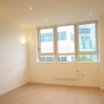 Bright empty room with large window and wood floor.