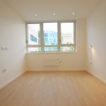 Empty room with large windows and wooden floor.
