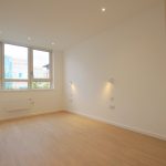 Bright empty room with large windows and wooden floor.