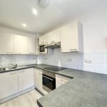 Modern kitchen with white cabinets and appliances.