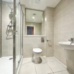 Modern bathroom with shower, toilet, and sink.