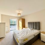 Modern bedroom with double bed and window view.