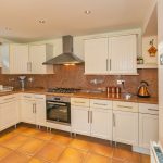 Modern kitchen with white cabinets and tiled floor.