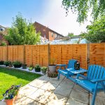 Sunny garden with blue chairs and wooden fence.