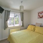 Cosy bedroom with yellow bedding and window view.