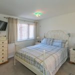 Cosy bedroom with bed, drawers, and TV.
