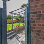 Garden view through open gate with terrace.