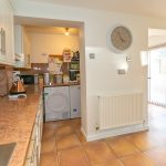 Modern kitchen with appliances and light tiled flooring.