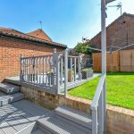 Sunny garden with patio and fence.