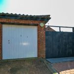 Brick garage with closed white door and side gate.