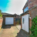 Brick garage and driveway with white doors.