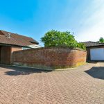 Brick driveway leading to garage, sunny day.