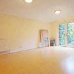 Empty room with wooden flooring and French doors.