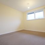 Empty room with beige carpet and large window.