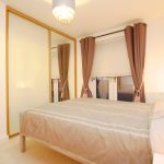 Modern bedroom with neutral decor and large window.