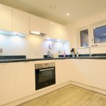 Modern kitchen with white cabinets and appliances.