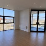 Modern empty flat with large windows and balcony view.