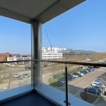 View from balcony overlooking car park and buildings.