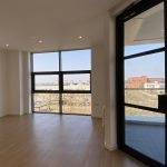 Bright modern flat with large windows overlooking cityscape.