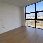 Empty room with large window and wooden floor.