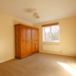 Sunny bedroom with wardrobe and window view.