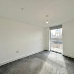 Empty room with large window and grey carpet.