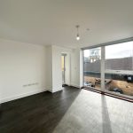 Modern flat with large windows and wooden flooring.