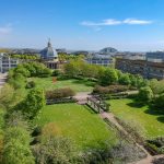 Campus with green park and large dome building.