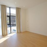 Empty room with large window and wooden floor.
