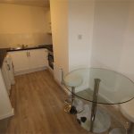 Small modern kitchen with round glass table.