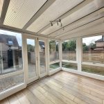 Bright conservatory with wooden floor and garden view.