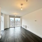 Bright empty room with large windows and wooden floor.