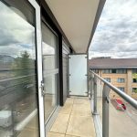 Modern flat balcony with glass railings and view.