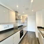 Modern kitchen with sleek cupboards and dark countertops.