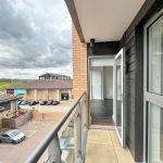Modern balcony view over car park and building.
