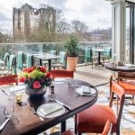 Modern restaurant with castle view and outdoor seating.