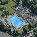 Aerial view of busy outdoor swimming pool and park.