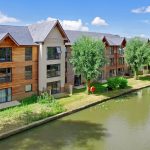 Riverside apartments with wooden exterior and trees