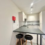 Modern kitchen with white cabinets and bar stools.