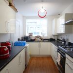 Modern kitchen with white cabinets and appliances.