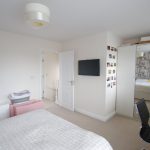 Modern bedroom with mirrored wardrobe and wall photos.