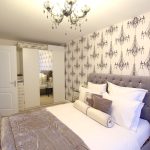 Elegant bedroom with chandelier wallpaper and plush bedding