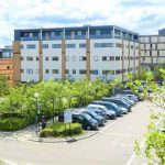 Office buildings and car park with greenery.