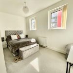 Modern bedroom with double bed and two windows.