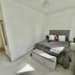 Modern bedroom with grey bedding and chandelier