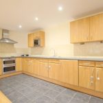 Modern kitchen with wooden cabinets and tiled floor.