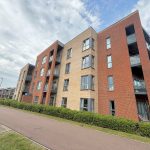 Modern apartment building with balconies and pathway.