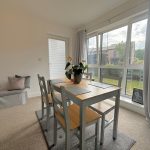 Bright dining room with large windows and wooden table.