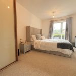 Modern bedroom with double bed and window view.